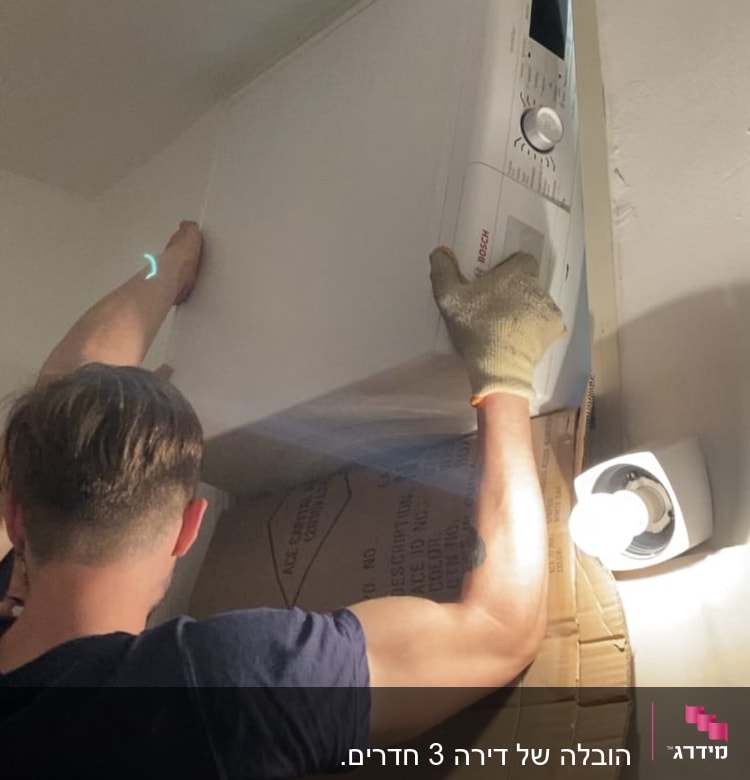 אדם מזיז מכונת כביסה עם קרטון להגנה